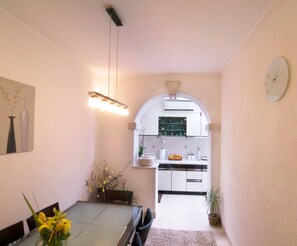 A modern kitchen with white cabinets, a built-in oven, and a clock on the wall.