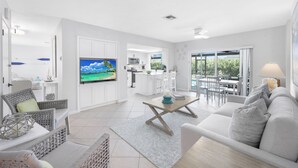 A modern living room with a sofa, TV, and dining area. - Nautical home w/ pool, grill & steps to shops (Marco Island)