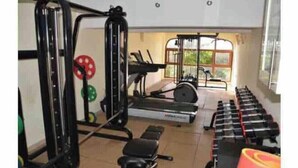 Un gimnasio con equipo de levantamiento de pesas, cintas de correr y máquinas de cardio.