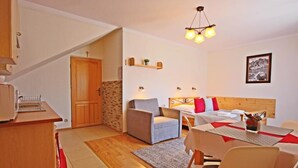 A cozy room with a bed, a sofa, a dining table, and a kitchen area. - Willa u Bachledów (Zakopane)