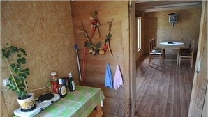 A wooden interior with a dining area, a small kitchen with a stove, and a wall-mounted TV. - Willa u Bachledów (Zakopane)