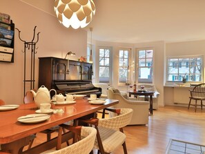 A dining area with a piano, a table set for four, and a large window with a view.