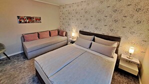 Une chambre à coucher avec un lit double, un canapé, une table de chevet avec une lampe et un luminaire au plafond.