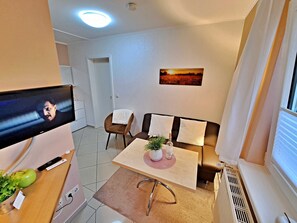 Un soggiorno moderno con una TV a schermo piatto, un divano, un tavolino da caffè e una finestra con persiane.