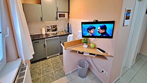 Une cuisine compacte équipée d’un four à micro-ondes, d’un évier et d’un téléviseur fixé au mur.