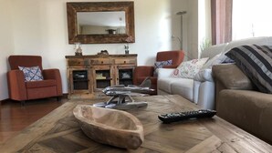 A living room with a wooden coffee table, two armchairs, a sofa, a TV, and a wooden cabinet. - Margasol - Housing for Tourist Use (PEDREZUELA)