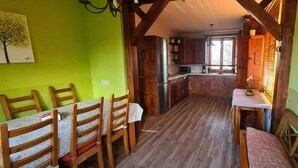 A dining area with wooden chairs and a table, a kitchen with wooden cabinets and a refrigerator, and a bright green wall. - Margasol - Housing for Tourist Use (PEDREZUELA)