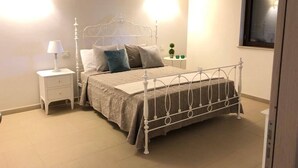 A bedroom with a metal bed frame, a bedside table with a lamp, and a small potted plant.