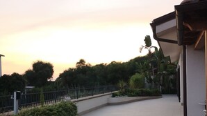 A spacious outdoor area with a curved pathway, surrounded by greenery and a fence.