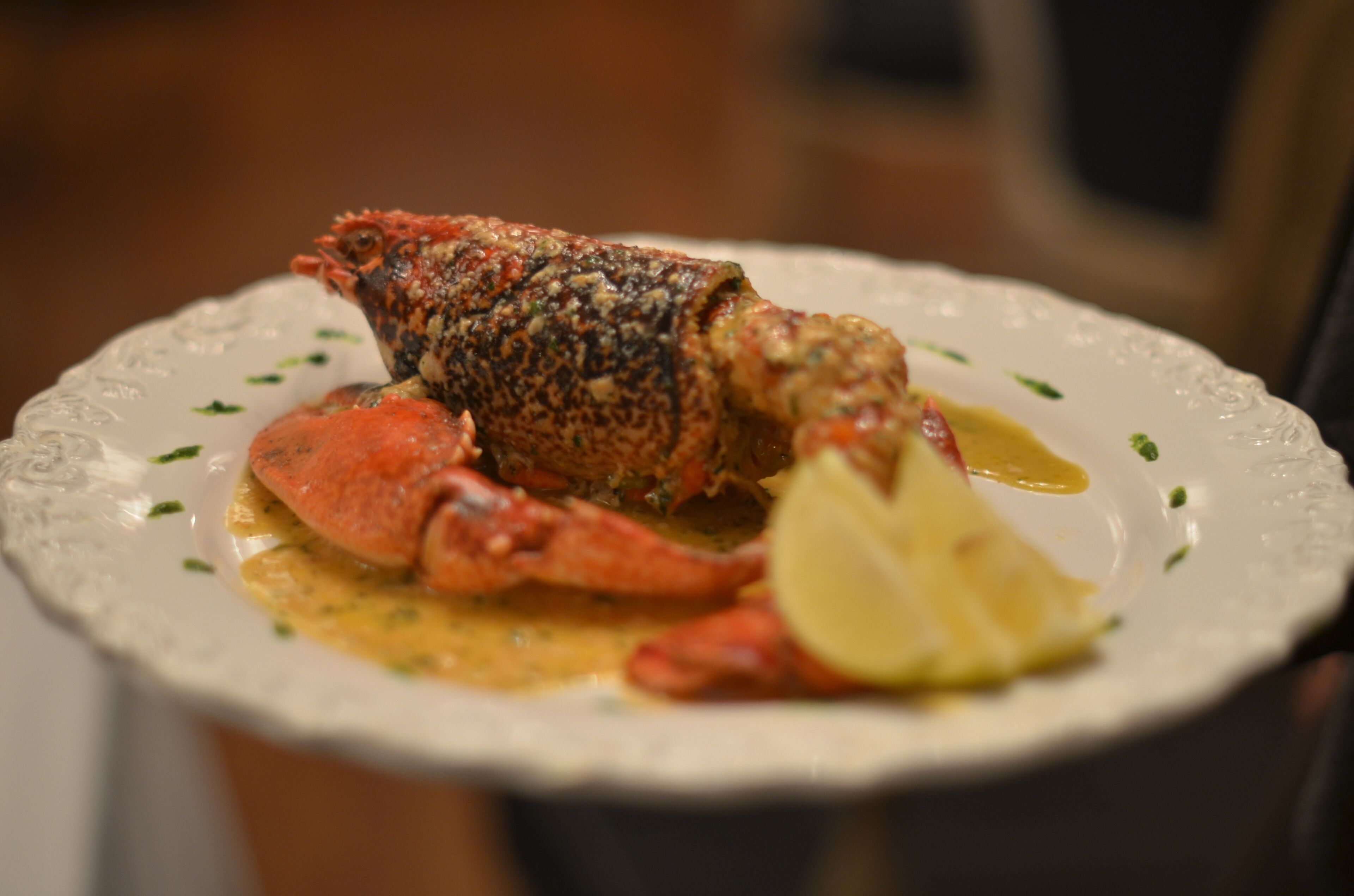 A lobster dish on a white plate with a lemon wedge.