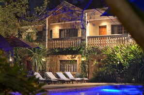 A two-story building with a balcony, a swimming pool, and lounge chairs. - The Riverside Hotel (Lubumbashi)
