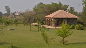Um gazebo em uma área gramada com um edifício ao fundo.