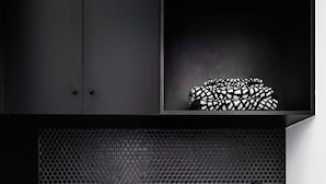 Une cuisine moderne équipée d’un lave-linge, d’un évier et d’un plan de travail noir.