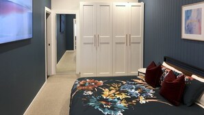 Une chambre avec un grand lit, une armoire, une lucarne et un tableau au mur.