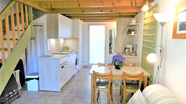 Una cocina compacta con lavadora, un comedor con mesa y sillas, y una escalera.