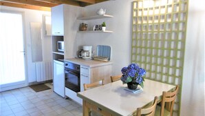 Una cocina compacta con mesa, sillas, refrigerador, microondas y cafetera.