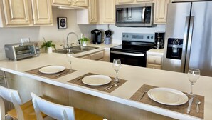 A modern kitchen with a central island, stainless steel appliances, and light wood cabinetry.