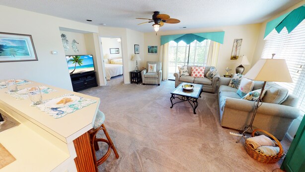 A living room with a television, a dining table, a sofa, and a floor lamp.