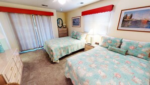A bedroom with two beds, a dresser, a nightstand, a lamp, and a framed picture on the wall.