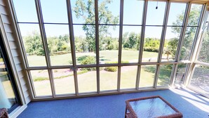 A room with large windows offering a view of a well-maintained lawn and trees.