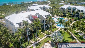A resort with multiple buildings, a central pool, and a view of the ocean.