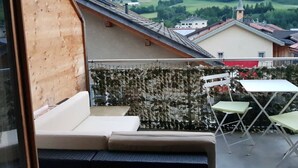 A balcony with a wooden slat wall, a sofa, and two chairs.