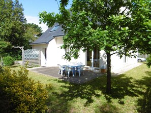 A house with a patio, a tree, and a car in the background.