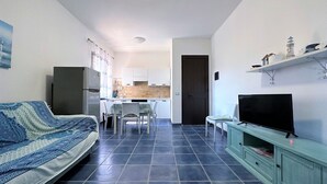 Ein Wohnzimmer mit einer Couch, einem Fernseher und einem Essbereich mit Stühlen und einem Tisch.