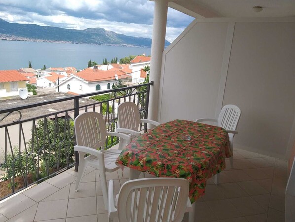 A balcony with a table and chairs, overlooking a lake and buildings.