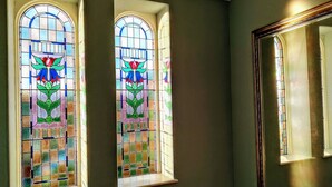 Deux vitraux ornés de motifs floraux, un miroir et un mur sombre.
