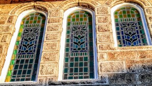 Un bâtiment doté de trois fenêtres en arc surmontées de vitraux aux motifs complexes.