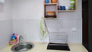 A compact kitchen with a sink, a metal drying rack, and shelves holding dishes and cups. - Fontanskaya doroga 16/5 (Одесса)