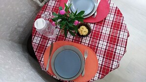 A round table with a red and white checkered tablecloth, a glass pitcher, a small bowl of cookies, and a potted plant with pink flowers. - Fontanskaya doroga 16/5 (Одесса)
