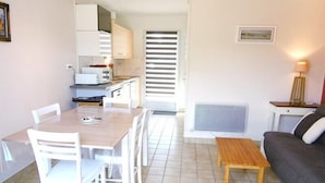 Un espacio habitable pequeño con una mesa de comedor y sillas, un sofá, una pequeña mesa de madera, un televisor y armarios de cocina.