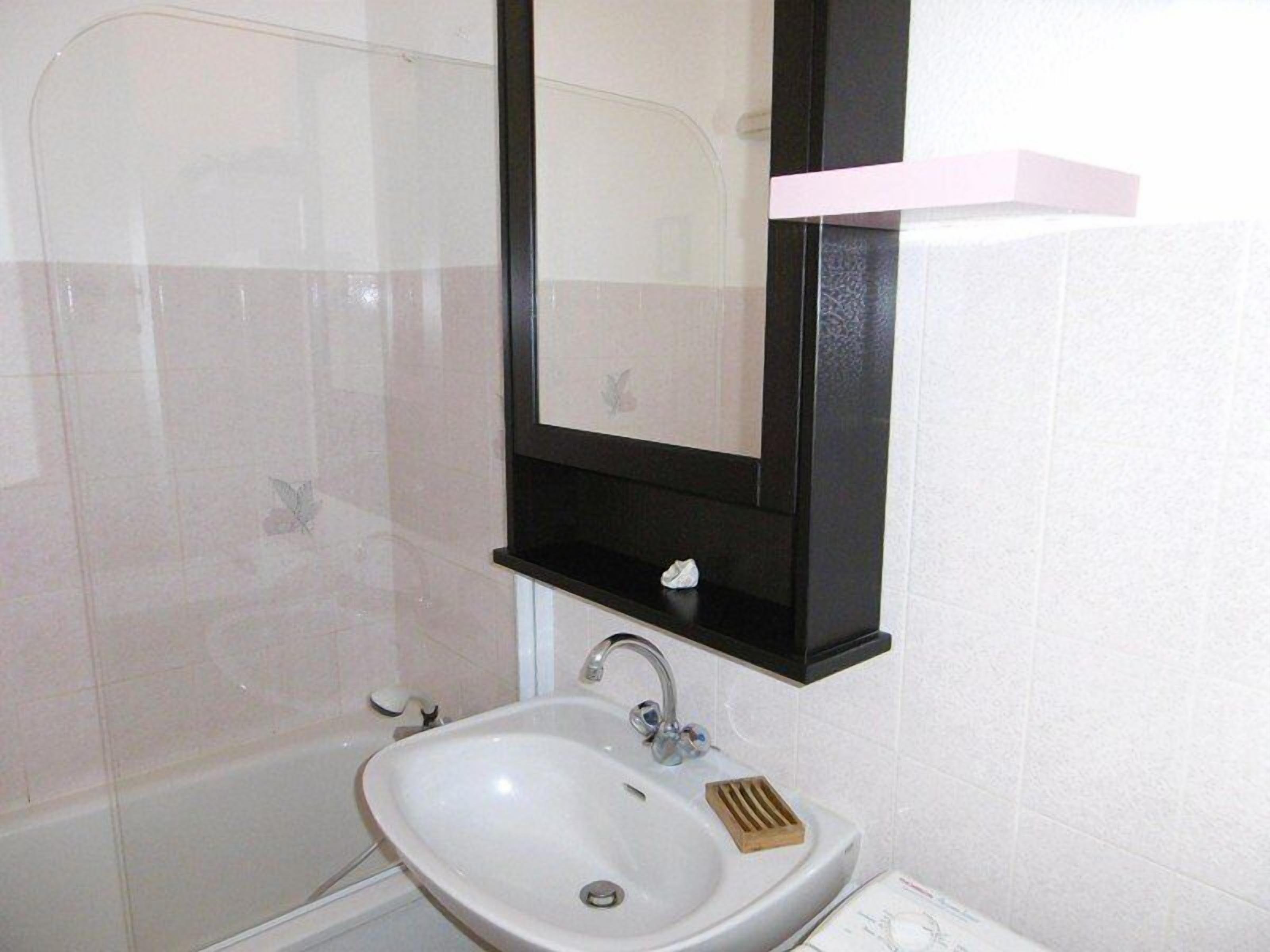 A bathroom with a white sink, a mirror, and a shower.
