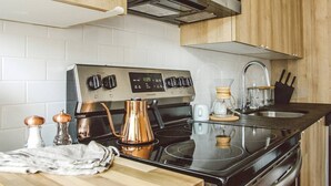 A kitchen with a stainless steel stove, a coffee maker, and a sink. - Billy Penn Studio at The Kestrel (Philadelphia)