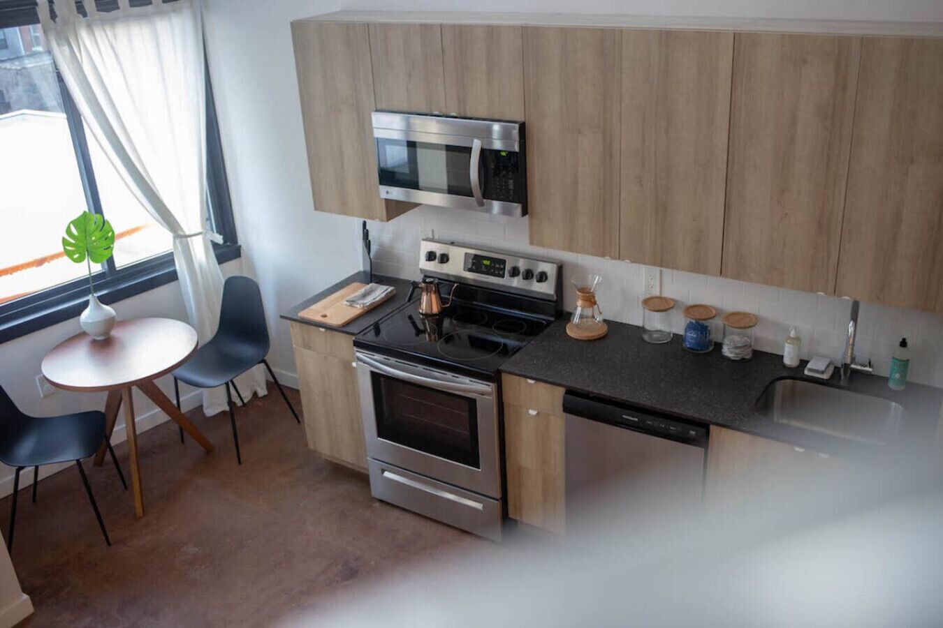 A compact kitchen with a microwave, stove, oven, and a small dining area with a table and chairs.