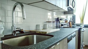 A kitchen with a double sink, white tiled backsplash, and a wooden countertop. - Poor Richard Studio at The Kestrel (Philadelphia)