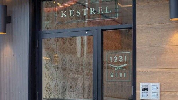 A hotel entrance with a glass door, a wooden wall, and a fire hydrant outside.