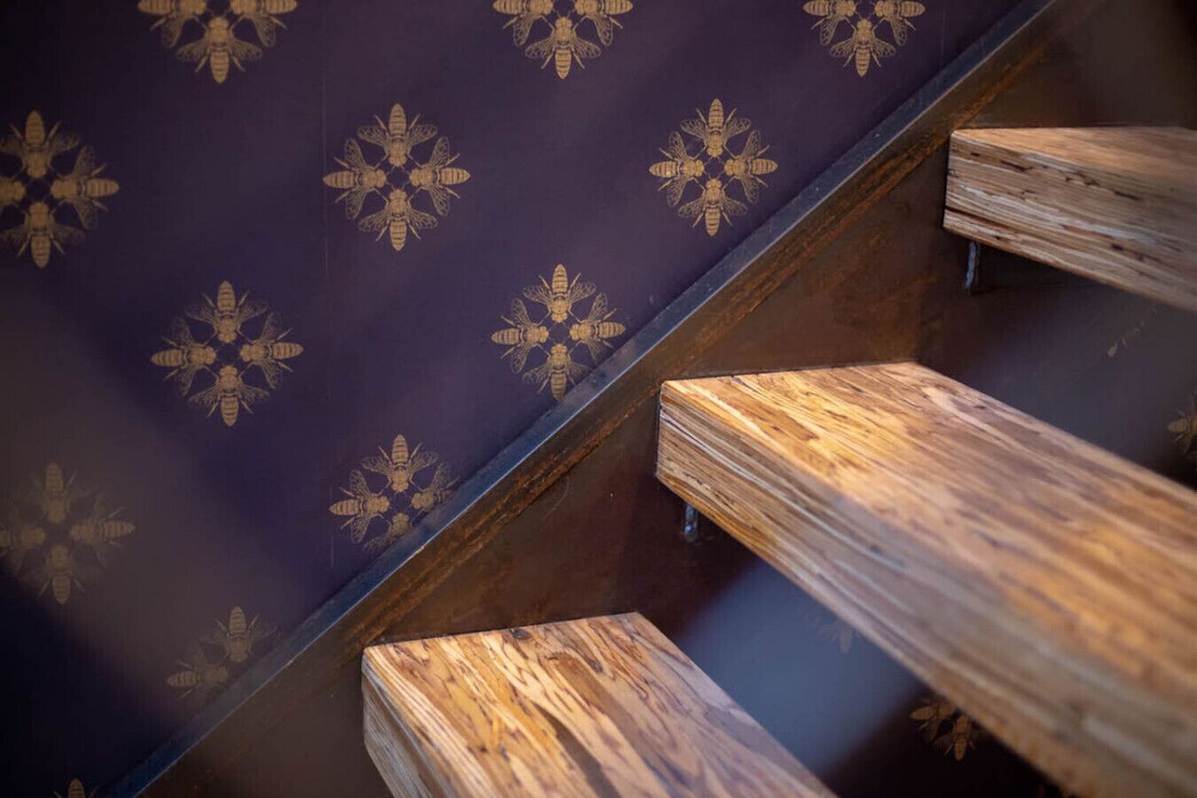 Una escalera de madera con un revestimiento mural oscuro y estampado.
