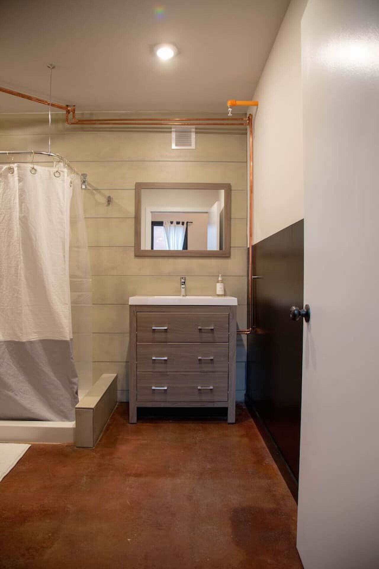 Un baño con ducha, un lavabo con espejo y una puerta.