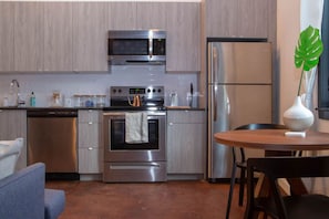 A modern kitchen with stainless steel appliances, a dishwasher, and a dining area with a table and chairs.