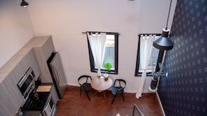A compact kitchen with modern appliances, a dining area with two chairs, and a staircase leading to another level. - Hive Room Loft at The Kestrel (Philadelphia)