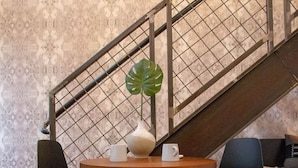 A modern interior with a staircase, a round wooden table with two chairs, a potted plant, and two white mugs. - Reading Viaduct Loft at The Kestrel (Philadelphia)