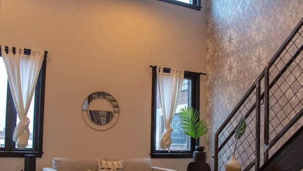A spacious living area with a sofa, a coffee table, and a staircase. - Reading Viaduct Loft at The Kestrel (Philadelphia)