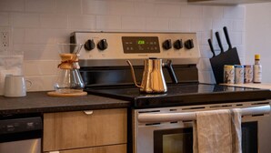 A kitchen with a stove, coffee maker, and a kettle on the counter. - Reading Viaduct Loft at The Kestrel (Philadelphia)