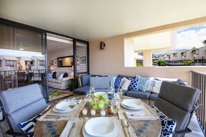 Un coin repas avec une table dressée pour deux personnes, un canapé et une cloison en verre.