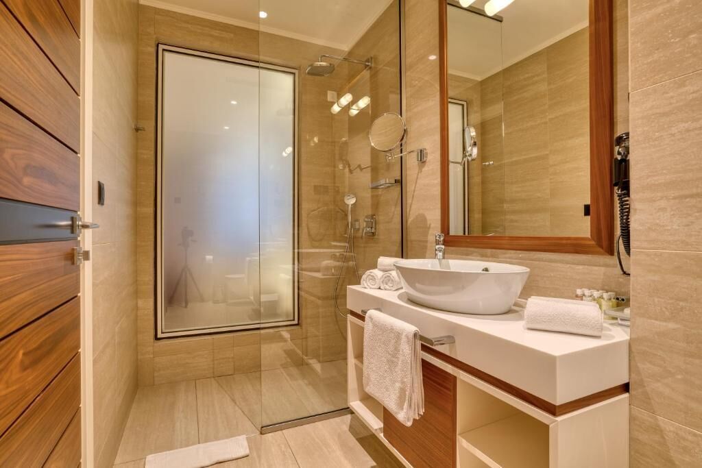 Ein modernes Badezimmer mit Duschkabine aus Glas, einem weißen Waschbecken und einem großen Spiegel.