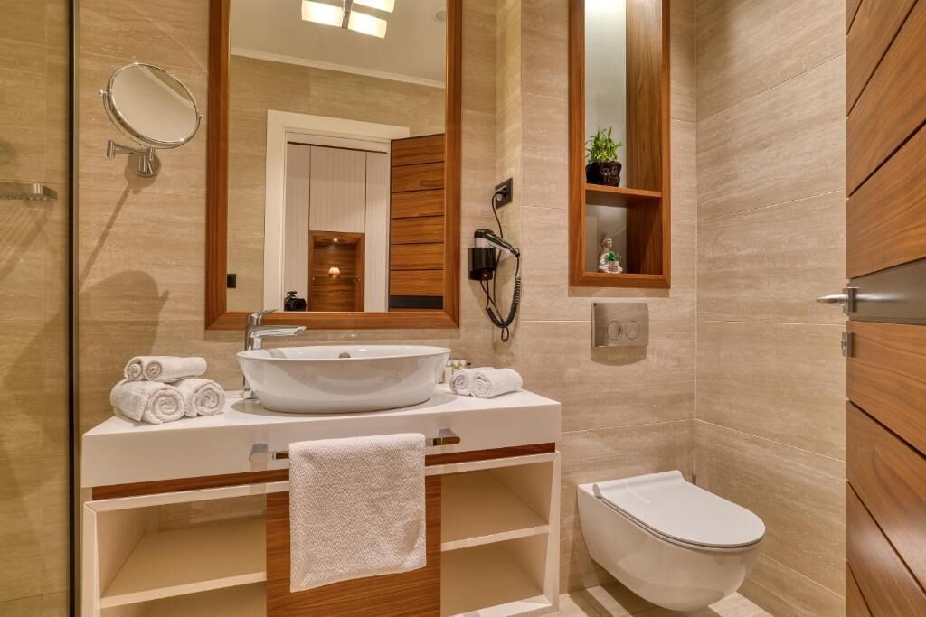 Un baño moderno con un espejo grande, un lavamanos, un inodoro y una ducha.