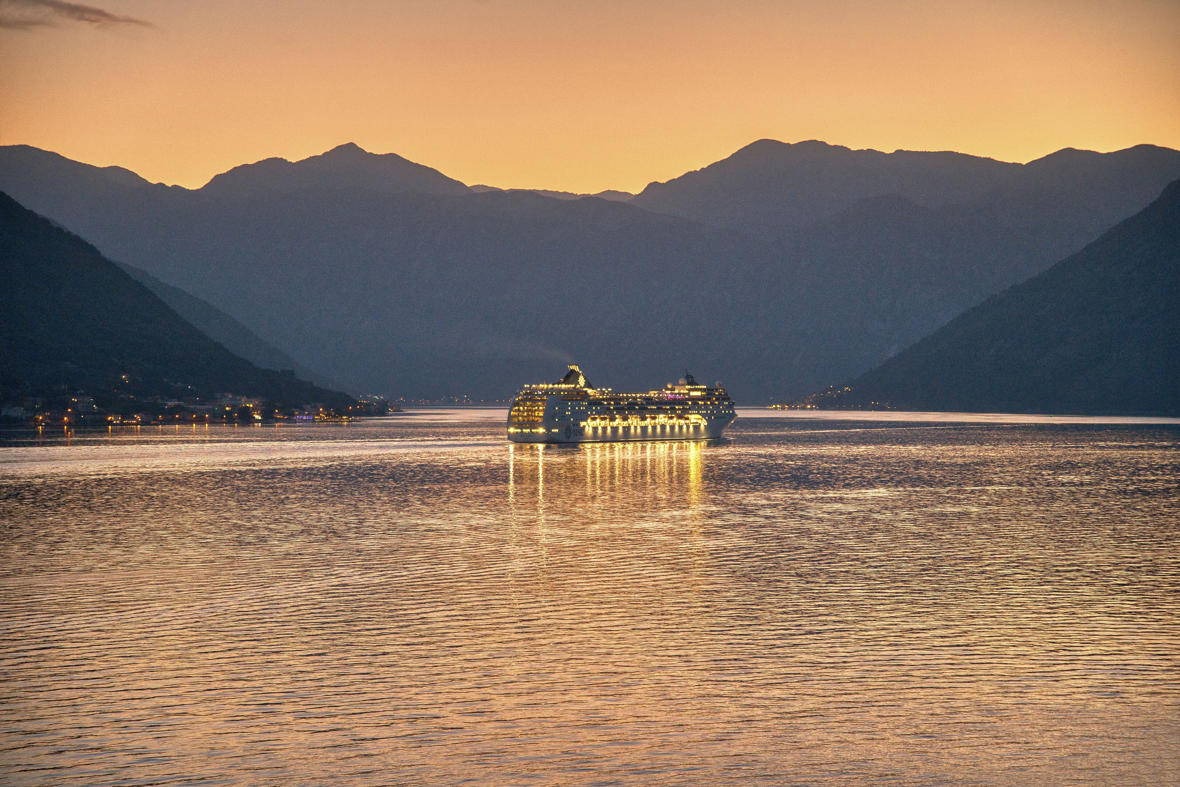 Ein Boot auf einem ruhigen See vor einer Bergkulisse.